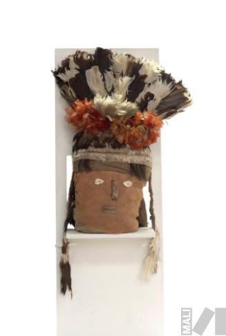 Cabeza de fardo funerario con rostro humano y tocado de
plumas